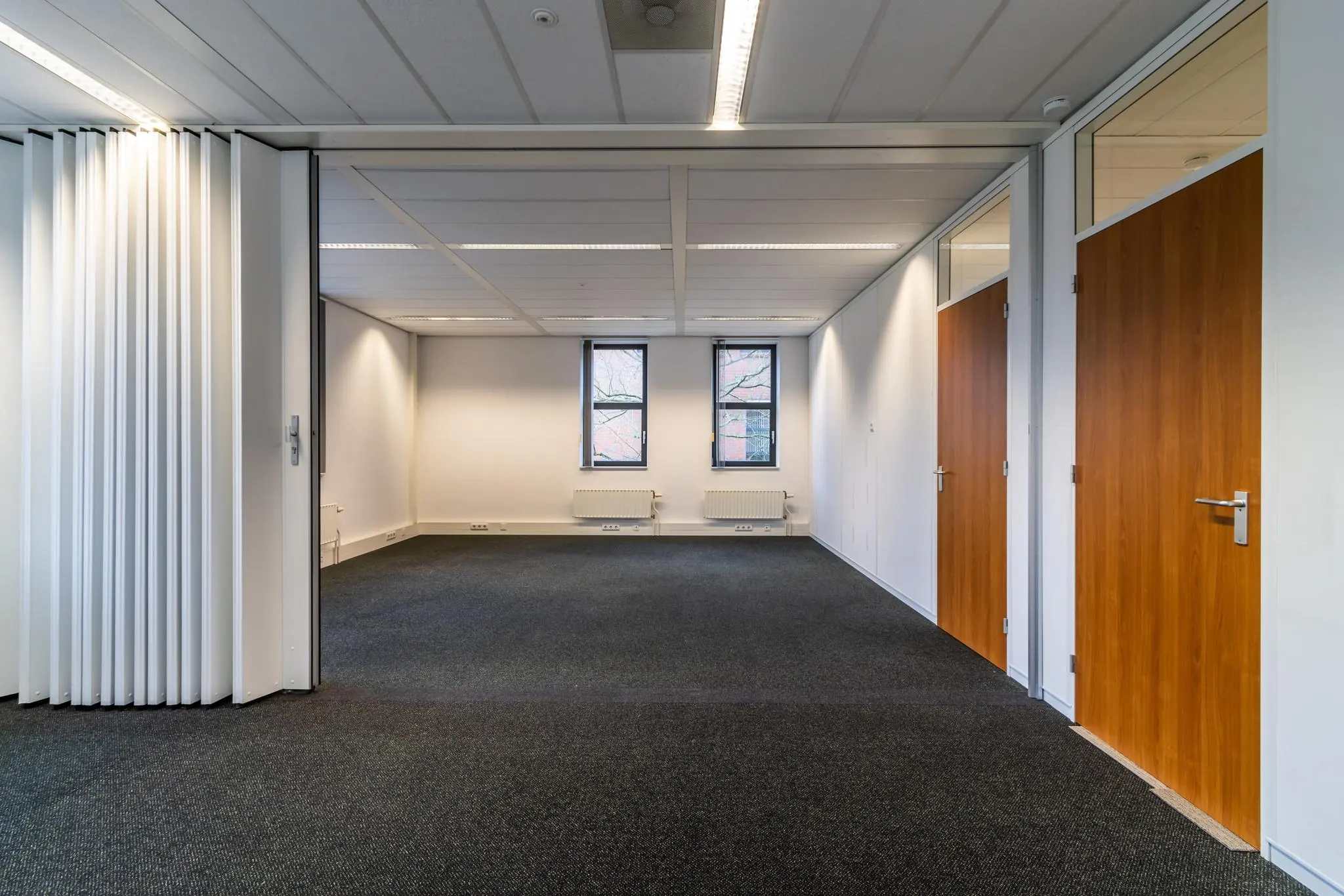 Leeg kantoorruimte aan de Lange Dreef met twee ramen, houten deuren en een scheidingswand.